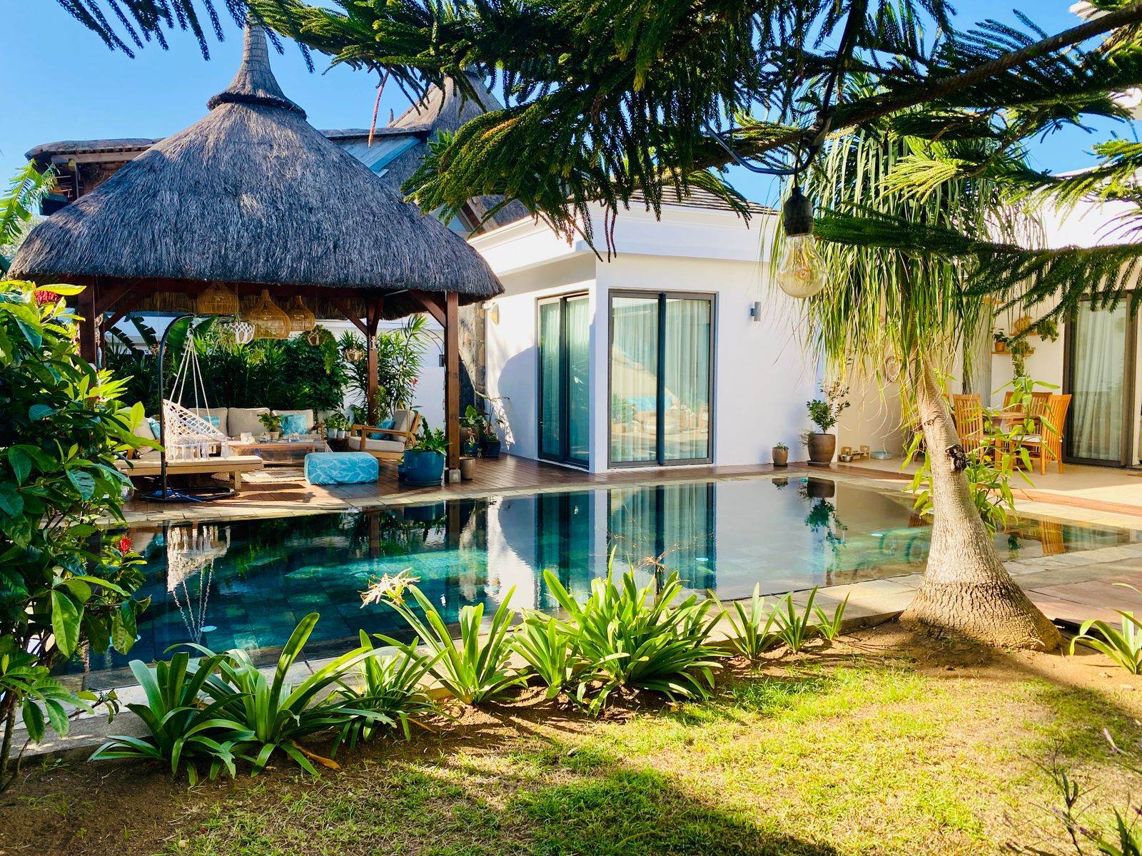 Swimming pool and thatched pavilion beside a tropical garden